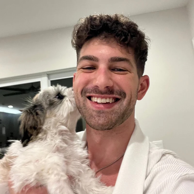 Matt smiling with Leo nuzzling his cheek