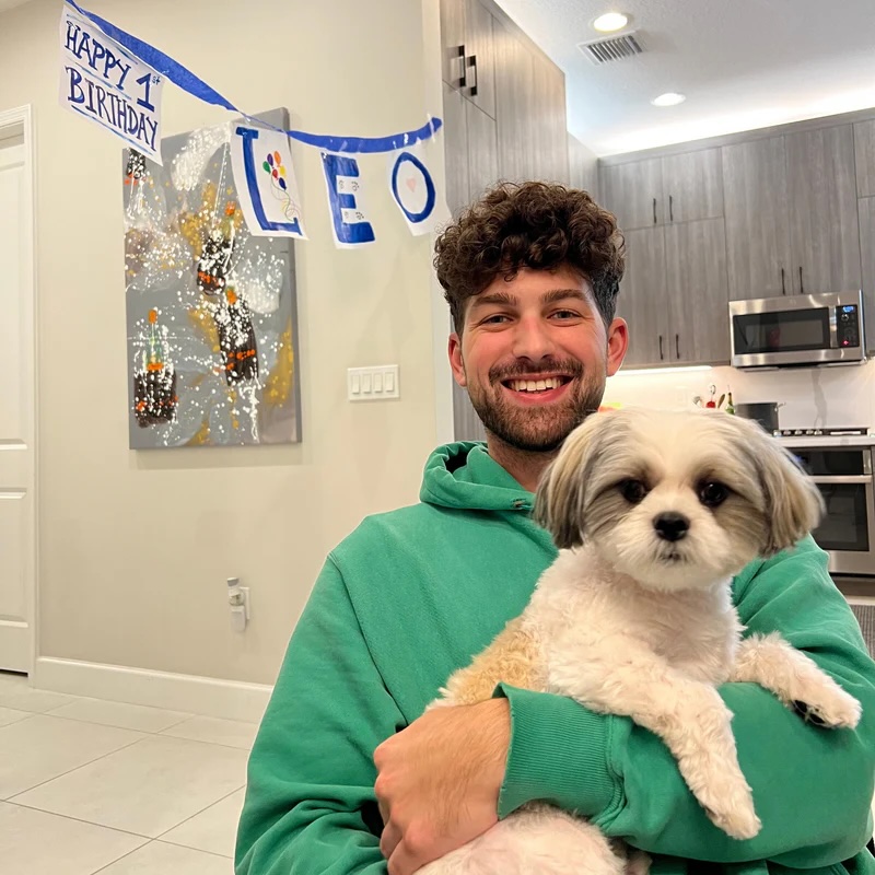 Matt holding Leo in front of a Happy 1st Birthday banner